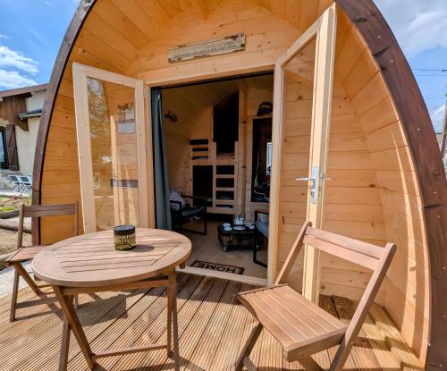 a wooden cabin with a table and chairs on a deck at Cabane - Nature & Détente in Lavoncourt