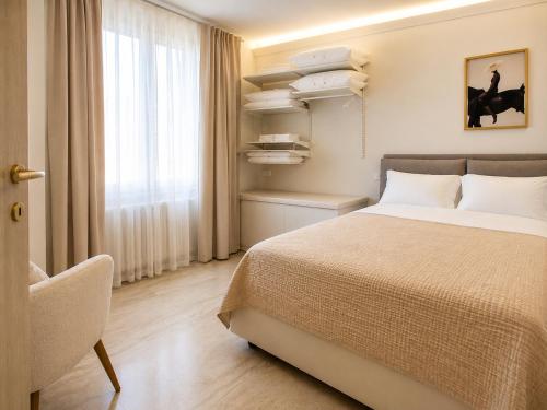 a bedroom with a bed and a chair and a window at Lecco Antico Pozzo - Modern Suite in Lecco