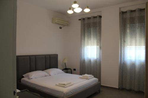 a bedroom with a bed with white sheets and windows at Vila Sosana in Qeparo