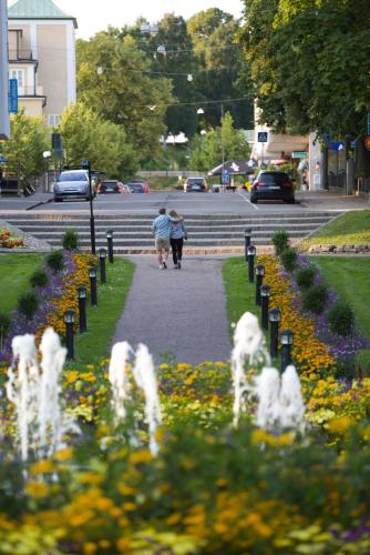 two people walking down a sidewalk next to a flower garden at Best Western Motala Stadshotell in Motala