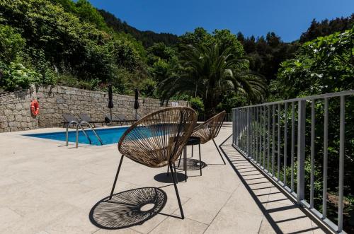 a patio with two chairs next to a pool at Chalet Villas Gerês in Geres