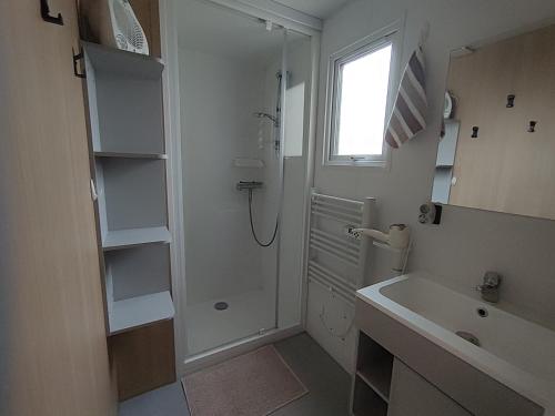 a white bathroom with a shower and a sink at Mobile home à Mimizan géré par un particulier in Mimizan