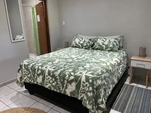 a bedroom with a bed with a green and white blanket at Amapondo in Port St. Johns