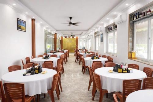 a row of tables in a restaurant with white tables and chairs at Hottel HÙNG PHƯƠNG cô tô in Đảo Cô Tô