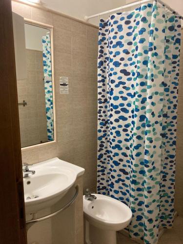 a bathroom with a sink and a toilet and a shower curtain at JERA Holiday Collection VULCANO UNO - Garden View in Vulcano
