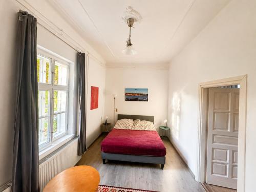 a bedroom with a red bed and a window at Dinnyés Kúria Dabas in Dabas