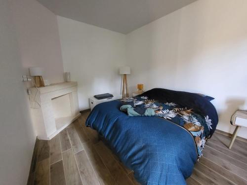 a bedroom with a bed with a blue comforter at L'Hirondelle in Fourges