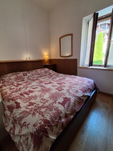 a bedroom with a bed with a red and white blanket at Cà Gianarín Authentic Dolomites Escape in Bocenago