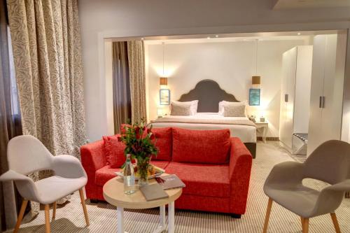 a hotel room with a red couch and a bed at Hotel Lac Leman, LES BERGES DU LAC in Tunis