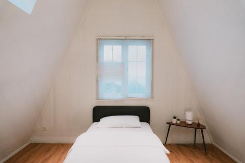 a white bedroom with a bed and a window at Suka Village 