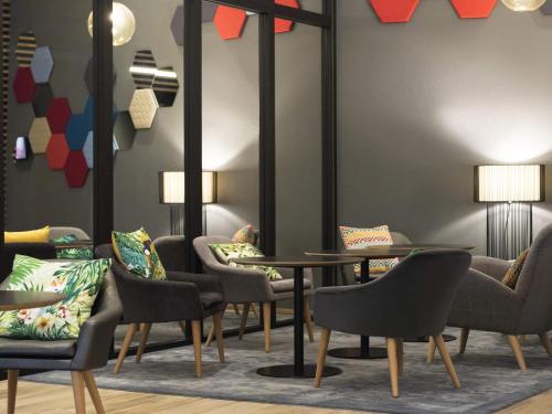 a waiting room with tables and chairs and lamps at Novotel Charleroi Centre in Charleroi