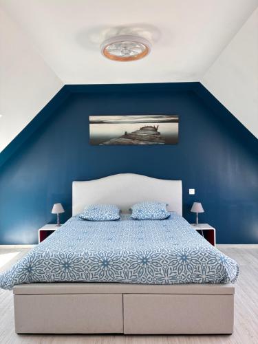 a blue bedroom with a bed with two pillows at Villa Métisse Ile et Villas Groix in Groix