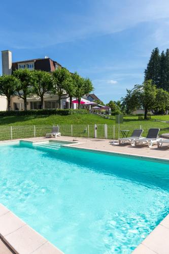 une grande piscine bleue avec des chaises et une maison dans l'établissement Logis Hotel Restaurant Spa Beau Site, à Luxeuil-les-Bains
