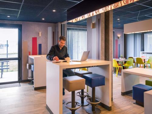 a man sitting at a table with a laptop at ibis budget Rennes Rte Lorient in Rennes