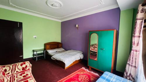 a bedroom with two beds and purple and green walls at Sumitra Niwas-Home Away from Home in Bālāju