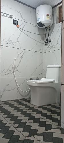 a bathroom with a toilet and a hair dryer on the wall at Mount Star Home Stay in Kakkabe