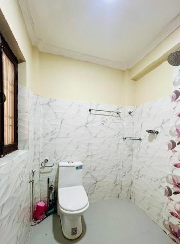 a white bathroom with a toilet and a shower at Sumitra Niwas-Home Away from Home in Bālāju