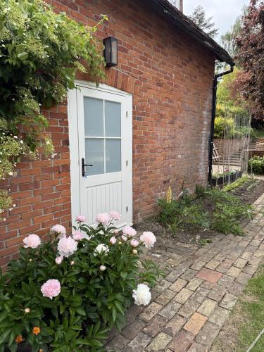a brick house with a white door and some flowers at The Coach House in Halstead