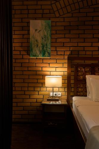 a lamp on a table in a bedroom with a brick wall at Platan in Samarkand