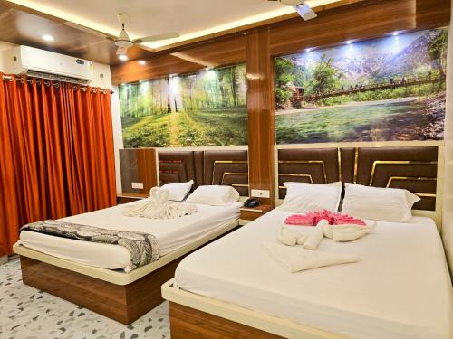 two beds in a room with a painting on the wall at Lokenath Resort in Tarapith