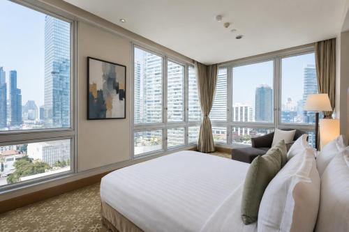 a hotel room with a bed and large windows at Ascott Sathorn Bangkok in Bangkok
