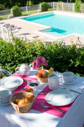 Una mesa con un mantel con comida al lado de una piscina. en Logis Hotel Restaurant Spa Beau Site, en Luxeuil-les-Bains
