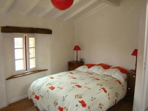 a bedroom with a white bed with red flowers on it at Mounismes du bas in Saint-Ouen-sur-Gartempe