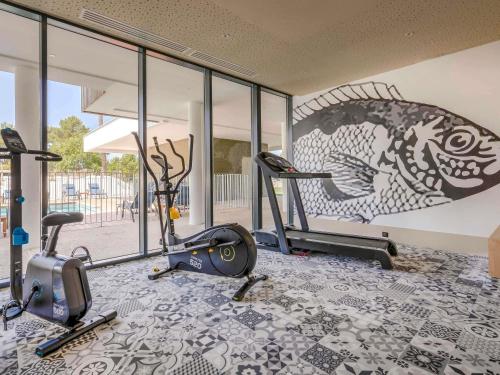a gym with two exercise bikes and a mural at ibis Styles Arcachon Gujan Mestras in Gujan-Mestras