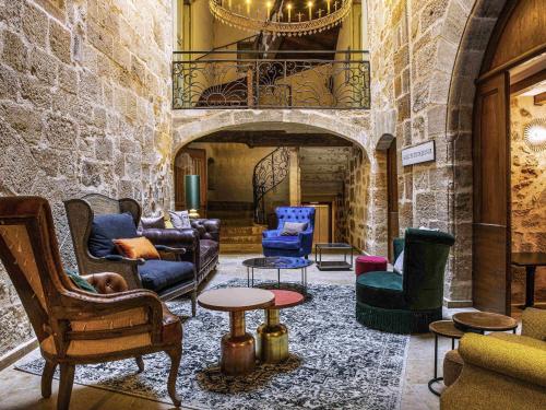 a lobby with chairs and tables in a building at Mercure Figeac Viguier du Roy in Figeac