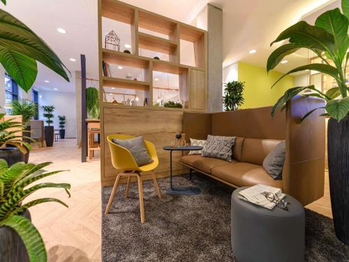 a living room with a couch and a plant at Ibis Styles Aschaffenburg in Aschaffenburg