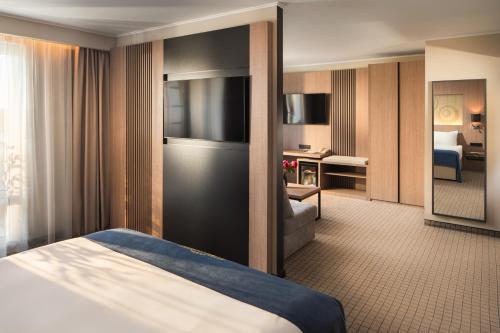 a hotel room with a bed and a living room at Landmark Creek Hotel & Wellness Plovdiv in Plovdiv