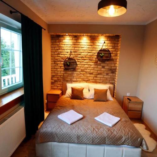 a bedroom with a large bed with a brick wall at Ewilla- apartamenty Wojcieszyce in Wojcieszyce