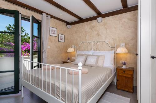 a bedroom with a white bed and a balcony at Holiday House - Old Olive in Porozina