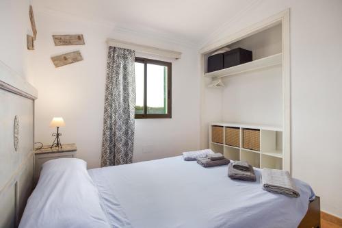 a white bedroom with a large bed and a window at Sa Vinya d'Es Trenc in Campos