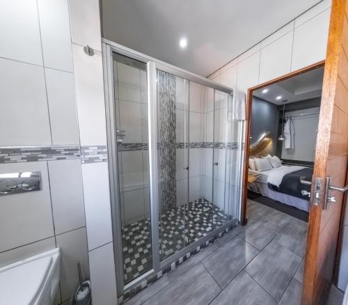 a bathroom with a shower and a bedroom at Nelspruit Lodge in Nelspruit