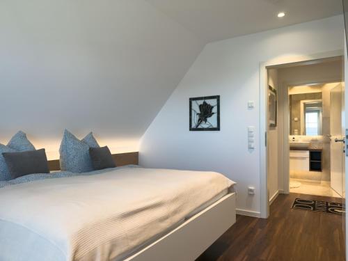 a bedroom with a large white bed with blue pillows at Haus Strandhafer in Wangerland