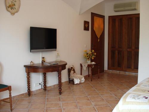 Cette chambre comprend une table et une télévision murale. dans l'établissement Les chambres de l'Hôte Antique, à Porto-Vecchio