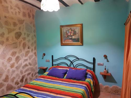 Dormitorio azul con cama con almohadas moradas en Casa Rural Valle del Cabriel, en Enguídanos