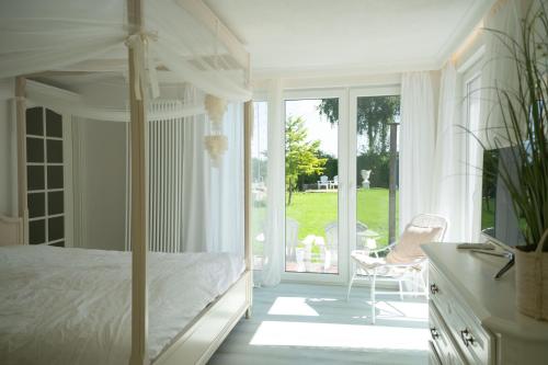 a white bedroom with a bed and a sliding glass door at Meer Weiss in Wangerland