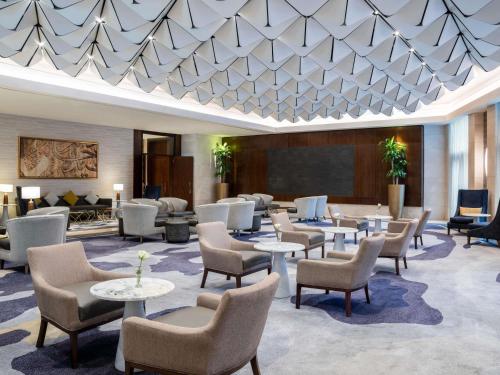 a hotel lobby with chairs and tables and a presentation at Movenpick Hotel & Residences Hajar Tower Makkah in Mecca