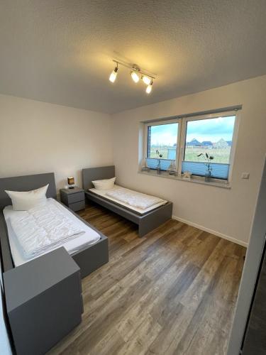 a bedroom with two beds and two windows at Koje Seelöwe in Wangerland