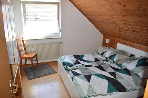 a bedroom with a bed and a chair and a window at Nordlys in Hooksiel