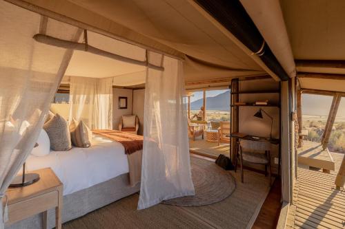 a bedroom with a bed and a view of the desert at Wolwedans Dune Camp in NamibRand