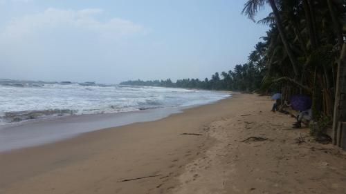 a beach with two people standing on the sand at Blue Waters in Matara