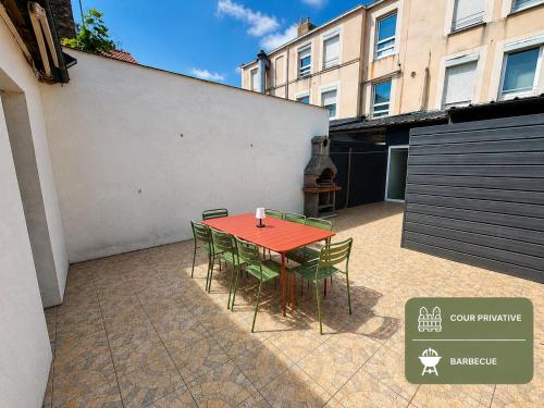 a red table and chairs in a courtyard with a building at L'Horizon Bleu - Appartement 4 chambres avec cour au centre Bourbourg in Bourbourg