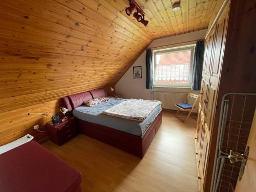 a small bedroom with a bed in a wooden ceiling at Haus Tillmann mit Hund in Hooksiel in Wangerland