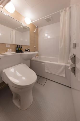 a bathroom with a toilet and a sink and a tub at Hotel New Green Plaza in Nagaoka