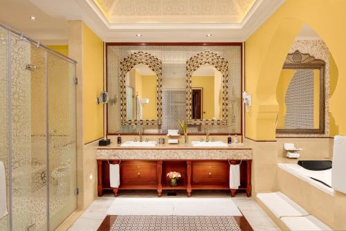 a bathroom with two sinks and two mirrors at Kampala Serena Hotel in Kampala