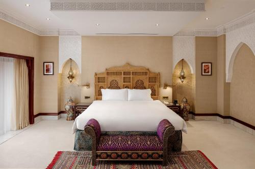 a bedroom with a large white bed and a bench at Kampala Serena Hotel in Kampala