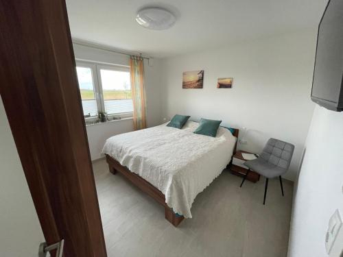 a bedroom with a bed and a chair and a window at Wangeroase in Wangerland